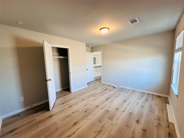 unfurnished bedroom with light wood-type flooring, a closet, visible vents, and baseboards