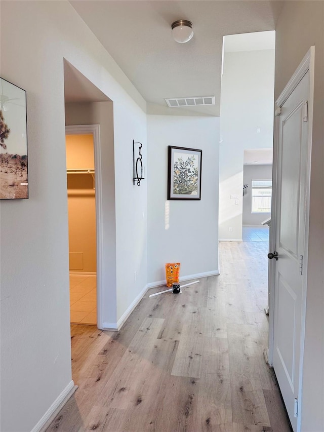 hallway with light wood-type flooring, visible vents, and baseboards