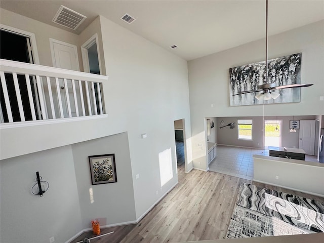 interior space featuring a towering ceiling, wood finished floors, visible vents, and baseboards