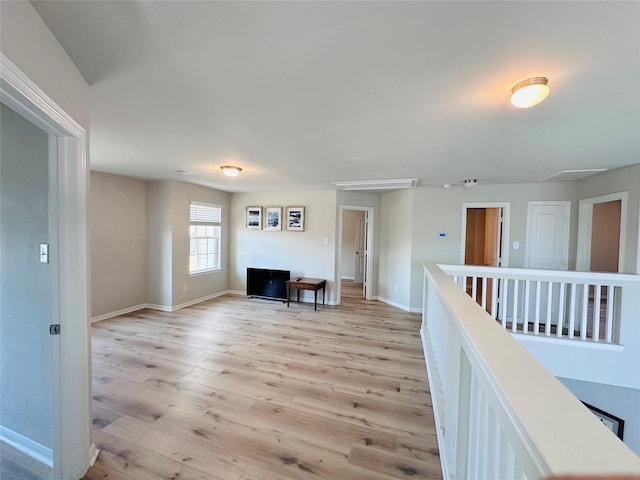 interior space with light wood finished floors, an upstairs landing, and baseboards