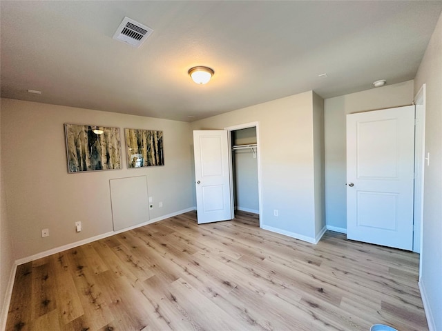 unfurnished bedroom with light wood-style flooring, a closet, visible vents, and baseboards