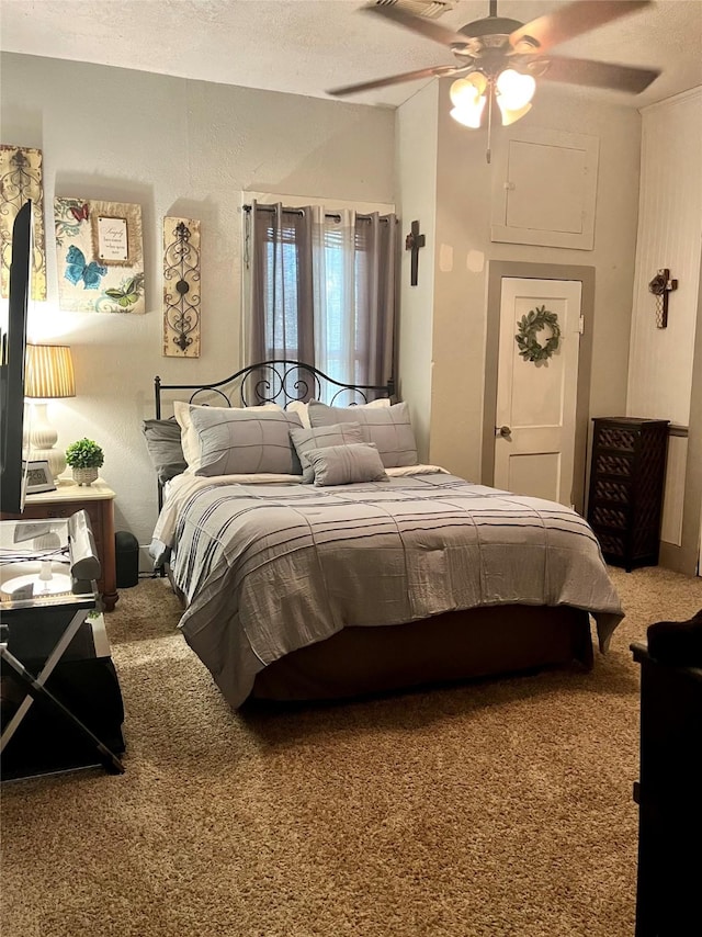 carpeted bedroom featuring a textured wall, ceiling fan, and a textured ceiling