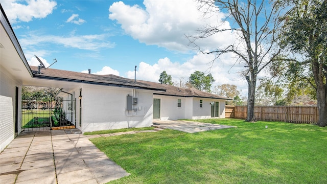 rear view of house featuring brick siding, a lawn, a patio area, and fence