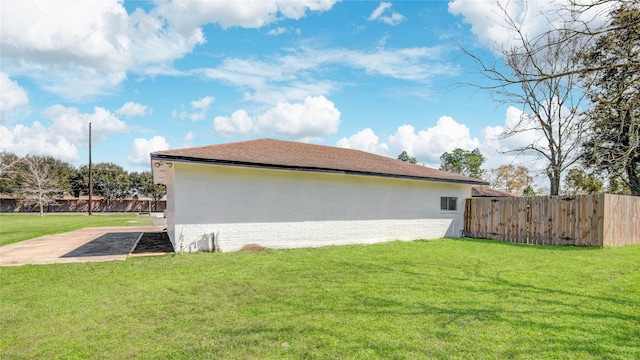 view of side of property with fence, a lawn, and brick siding