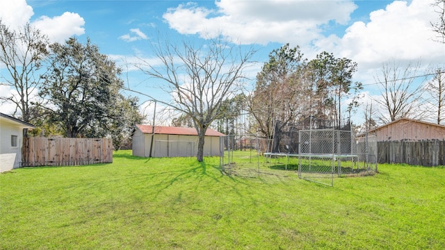 view of yard featuring an outbuilding, a trampoline, and fence