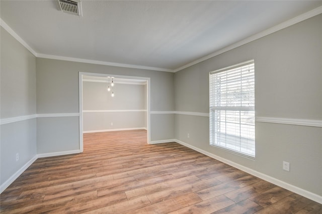 empty room with visible vents, crown molding, baseboards, and wood finished floors