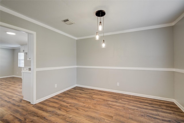 unfurnished room with ornamental molding, visible vents, baseboards, and wood finished floors