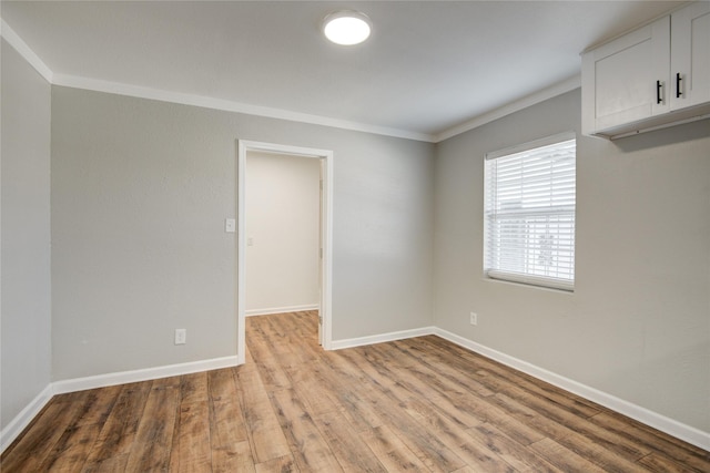 empty room with light wood-style flooring, baseboards, and ornamental molding