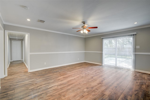 spare room featuring attic access, baseboards, visible vents, ornamental molding, and wood finished floors