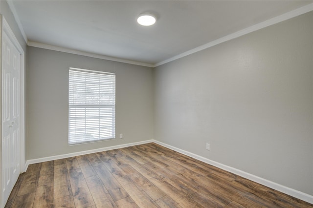 empty room with crown molding, dark wood finished floors, and baseboards