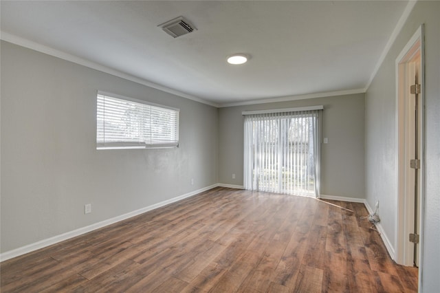 empty room with ornamental molding, dark wood-type flooring, visible vents, and baseboards