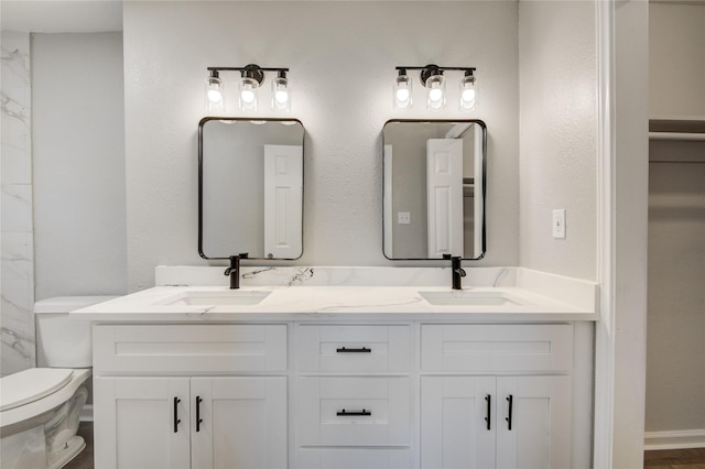 bathroom featuring toilet, double vanity, and a sink