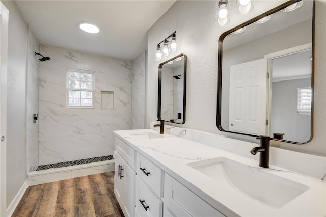 full bath featuring a marble finish shower, a sink, and wood finished floors