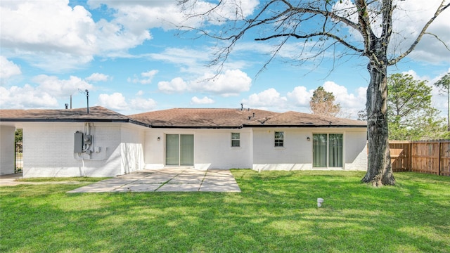 back of house featuring brick siding, a lawn, a patio area, and fence