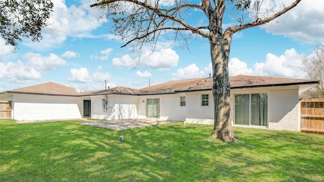 rear view of property with a yard, brick siding, a patio, and fence