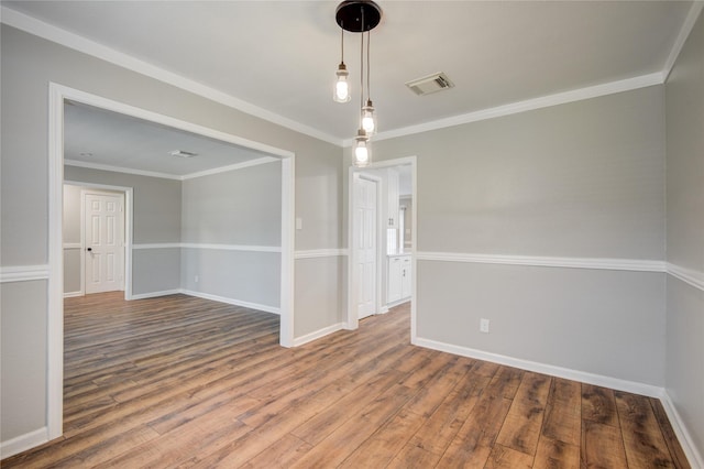 spare room featuring ornamental molding, visible vents, baseboards, and wood finished floors