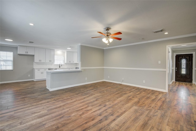 unfurnished living room featuring a wealth of natural light, visible vents, baseboards, and dark wood-style flooring