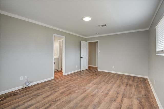 unfurnished room with visible vents, crown molding, baseboards, and wood finished floors