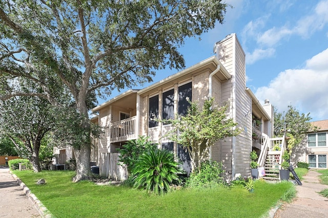 view of front facade featuring stairs, a chimney, and a front yard