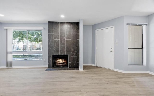 unfurnished living room with recessed lighting, a fireplace, baseboards, and wood finished floors