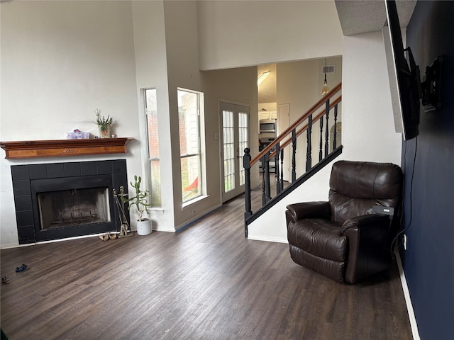 foyer with baseboards, visible vents, a tile fireplace, wood finished floors, and stairs