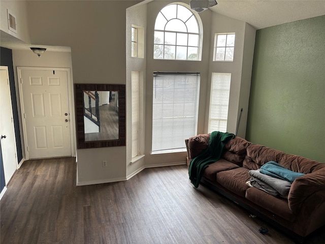 living room featuring high vaulted ceiling, baseboards, visible vents, and dark wood-type flooring