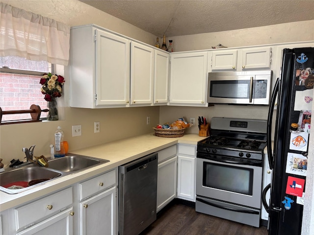 kitchen with dark wood-style flooring, stainless steel appliances, a textured ceiling, light countertops, and a sink