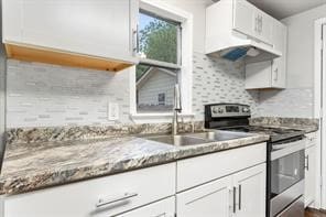 kitchen with stone countertops, decorative backsplash, stainless steel range with electric cooktop, white cabinetry, and a sink