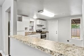 kitchen featuring freestanding refrigerator, white cabinets, and stainless steel range with electric cooktop