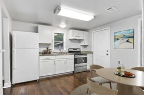 kitchen with dark wood-style floors, freestanding refrigerator, white cabinets, and stainless steel electric stove