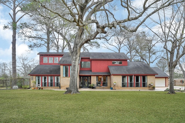 back of house featuring brick siding, a lawn, and fence