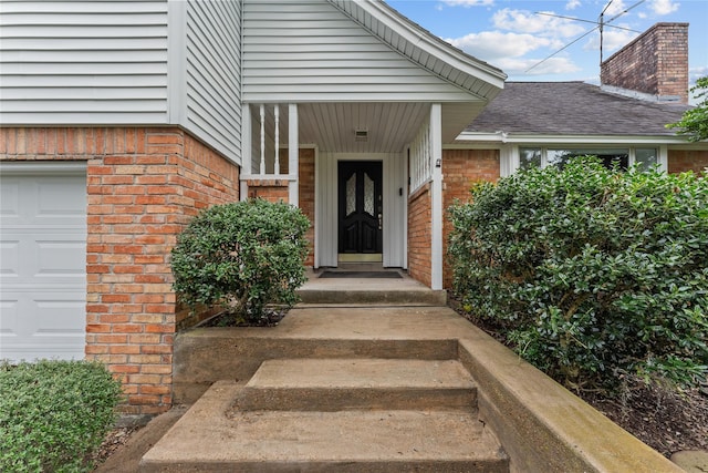 entrance to property featuring brick siding, a chimney, a shingled roof, and a garage