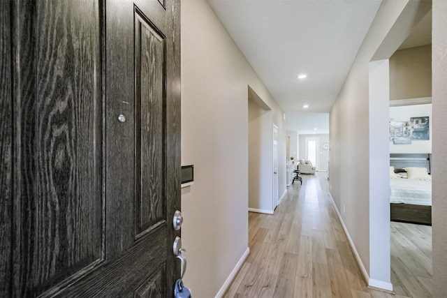 hallway featuring baseboards, recessed lighting, and light wood-style floors