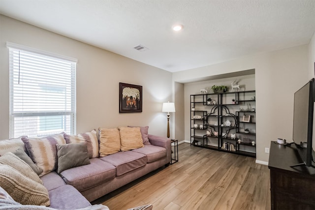 living area featuring visible vents, baseboards, and light wood finished floors