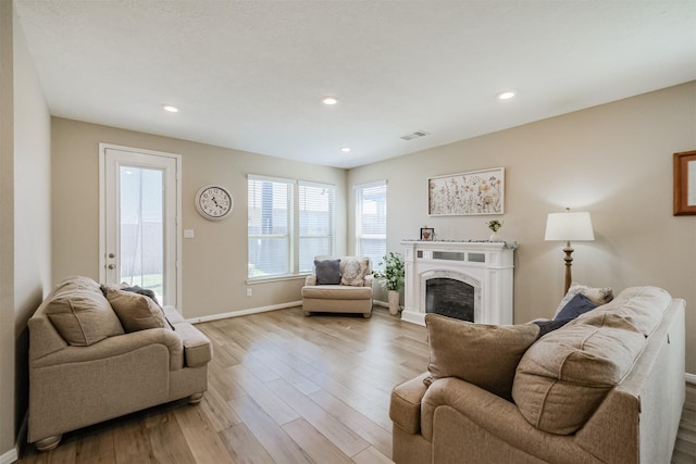 living area with light wood-style flooring, visible vents, baseboards, recessed lighting, and a fireplace