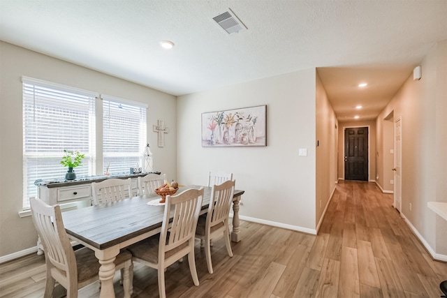 dining space with visible vents, light wood-style flooring, and baseboards
