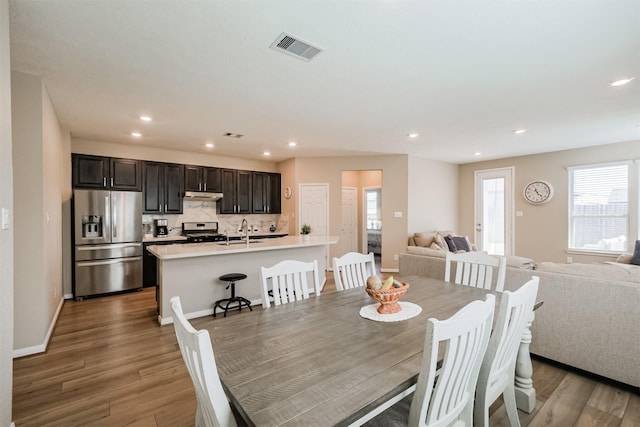 dining space featuring baseboards, visible vents, light wood finished floors, and recessed lighting