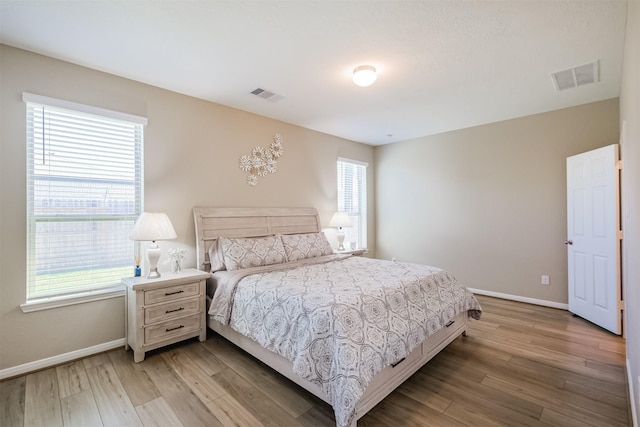 bedroom featuring visible vents, light wood-style flooring, and baseboards