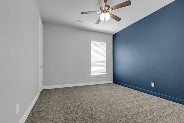 carpeted spare room with a ceiling fan, visible vents, and baseboards