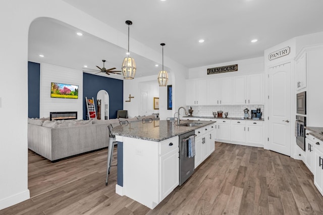 kitchen featuring a large fireplace, stainless steel appliances, wood finished floors, a sink, and tasteful backsplash