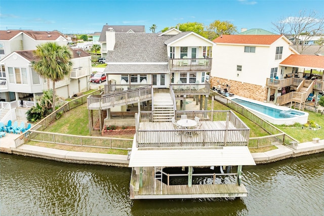 back of property with a balcony, a fenced backyard, a residential view, and a deck with water view