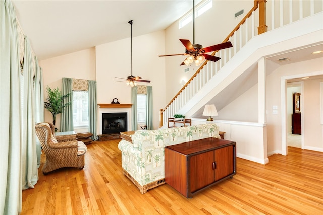 living room with light wood-type flooring, visible vents, and a fireplace with raised hearth