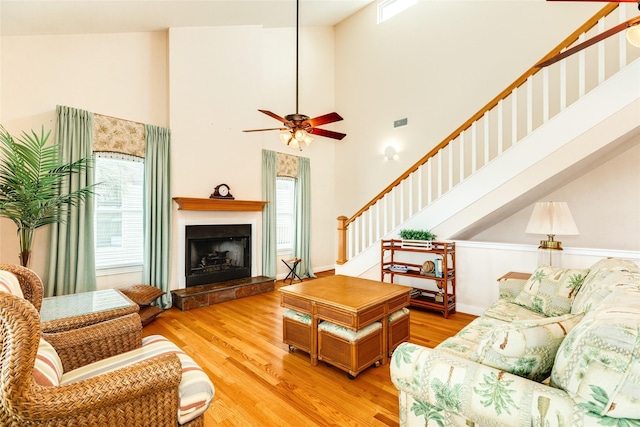 living room with a fireplace with raised hearth, plenty of natural light, and wood finished floors