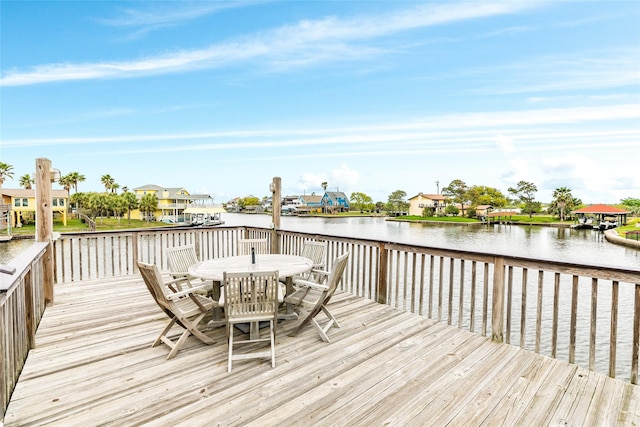 deck with a residential view, outdoor dining area, and a water view