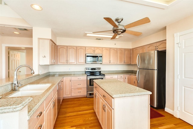 kitchen featuring light wood finished floors, appliances with stainless steel finishes, light brown cabinets, a sink, and light stone countertops