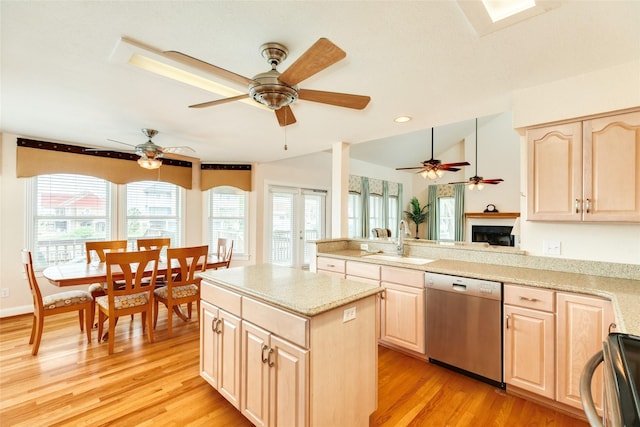 kitchen featuring stainless steel dishwasher, light brown cabinets, a sink, range, and a peninsula