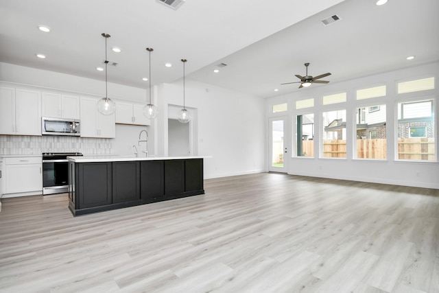 kitchen with appliances with stainless steel finishes, visible vents, decorative backsplash, and white cabinetry