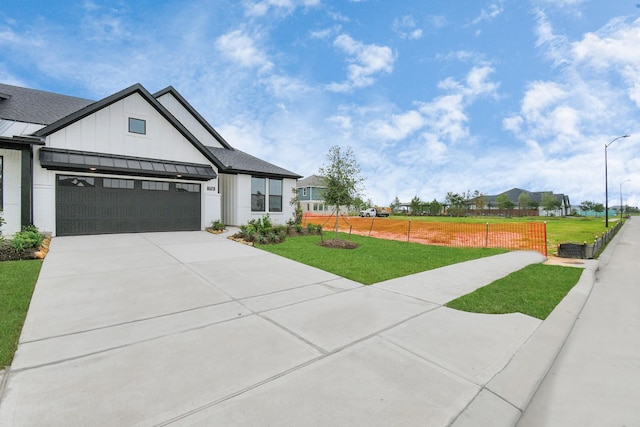 modern inspired farmhouse featuring concrete driveway, board and batten siding, a standing seam roof, fence, and a front lawn