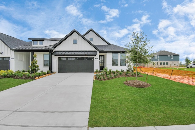 modern inspired farmhouse with a garage, concrete driveway, a standing seam roof, a front lawn, and board and batten siding