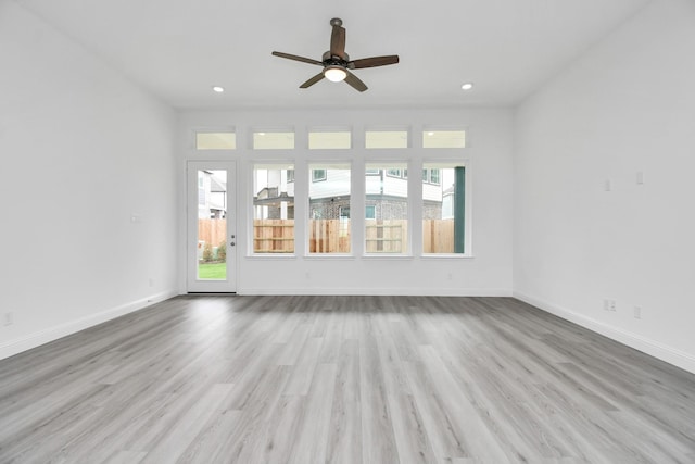 unfurnished living room featuring baseboards, recessed lighting, wood finished floors, and a healthy amount of sunlight